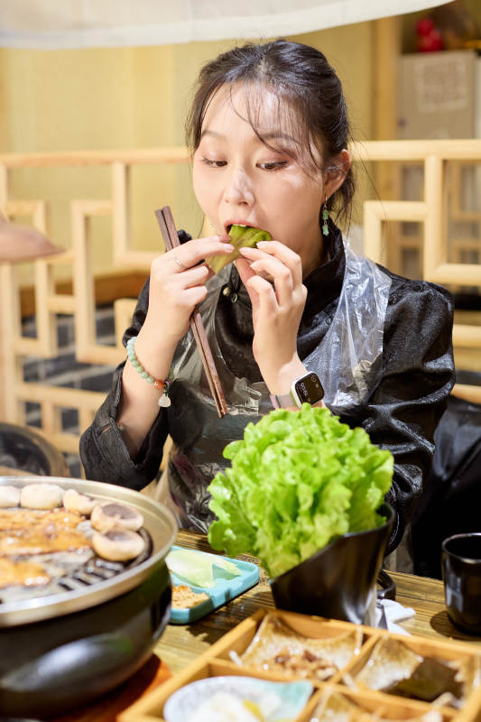 在韩式烤肉店享受美食的亚洲美女图片