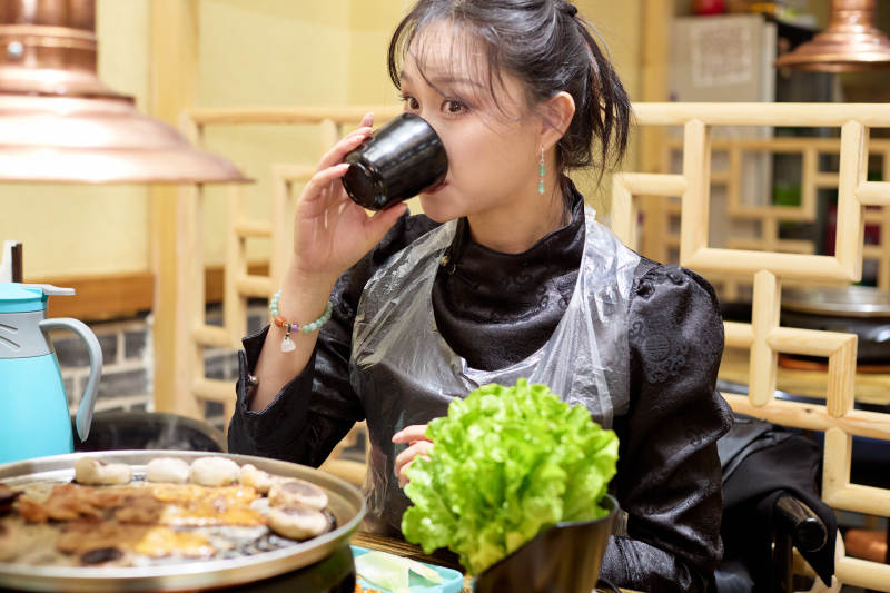 在韩式烤肉店享受美食的亚洲美女图片