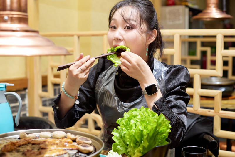 在韩式烤肉店享受美食的亚洲美女图片