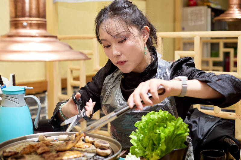 在韩式烤肉店享受美食的亚洲美女图片