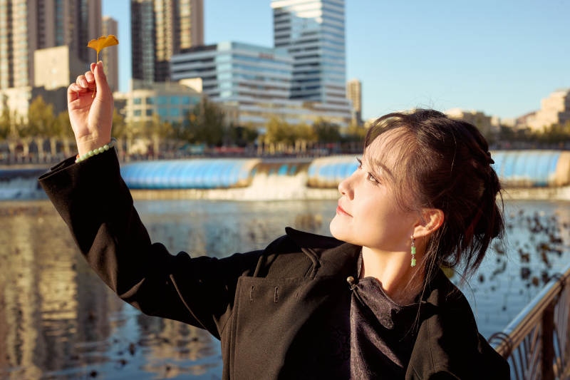 秋天在红叶遍布的河边拍照的亚洲女性图片