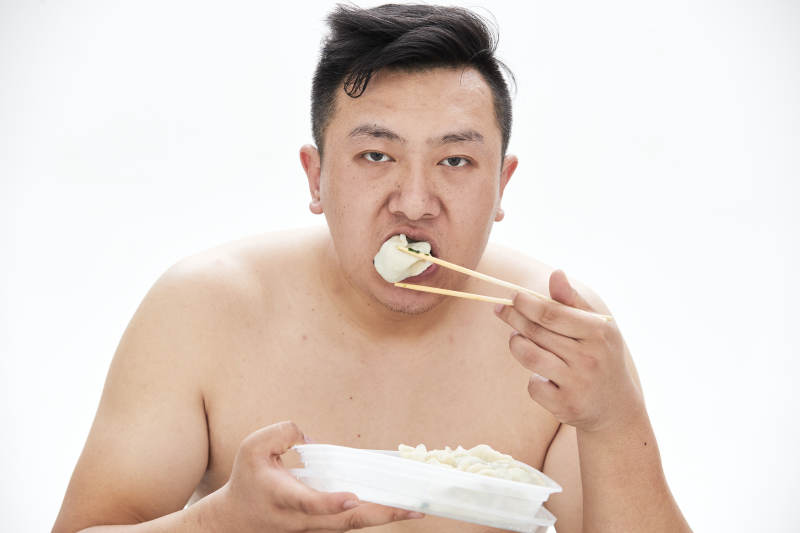 大吃特吃各种食物的肥胖亚洲男子图片
