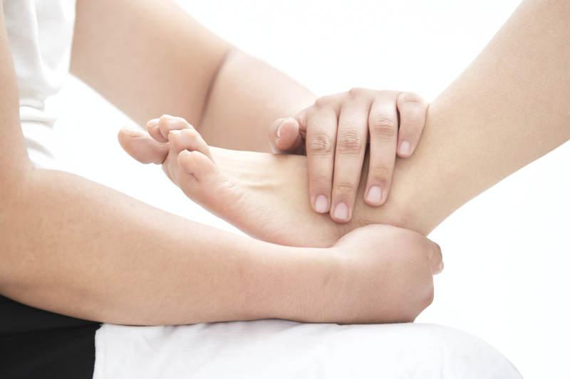 在白色背景上穿着黑色长袜的女人的苗条的腿图片