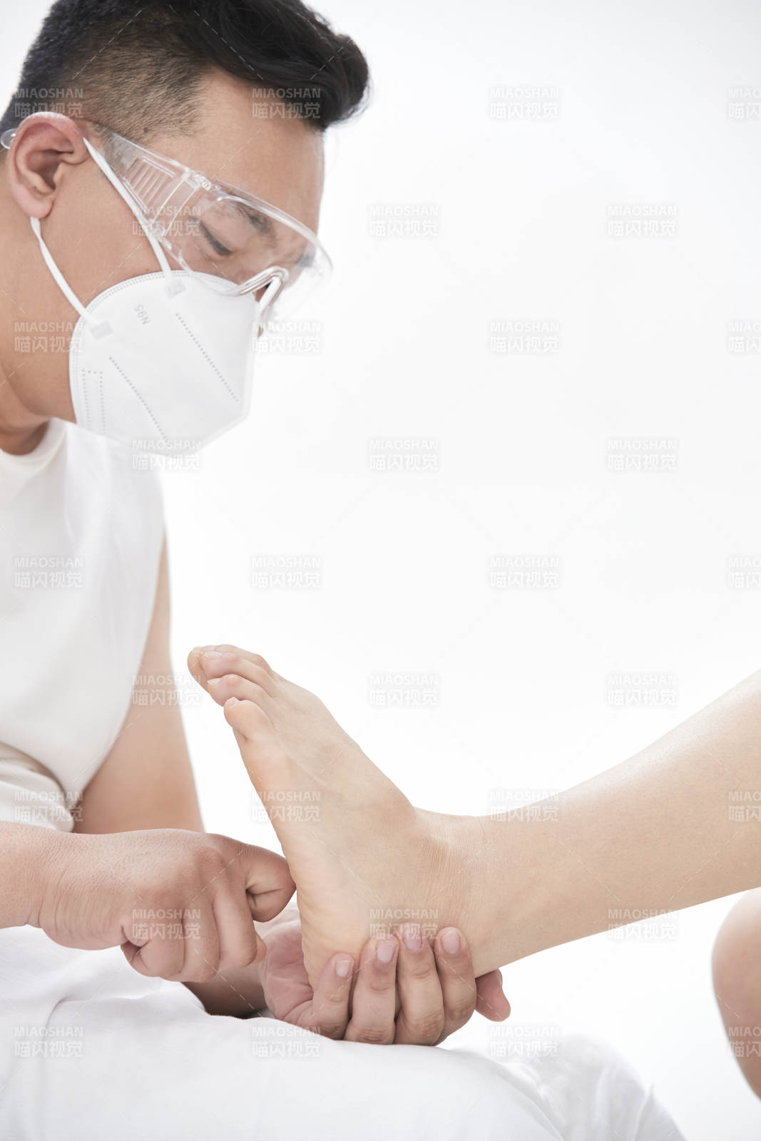 在白色背景上穿着黑色长袜的女人的苗条的腿图片