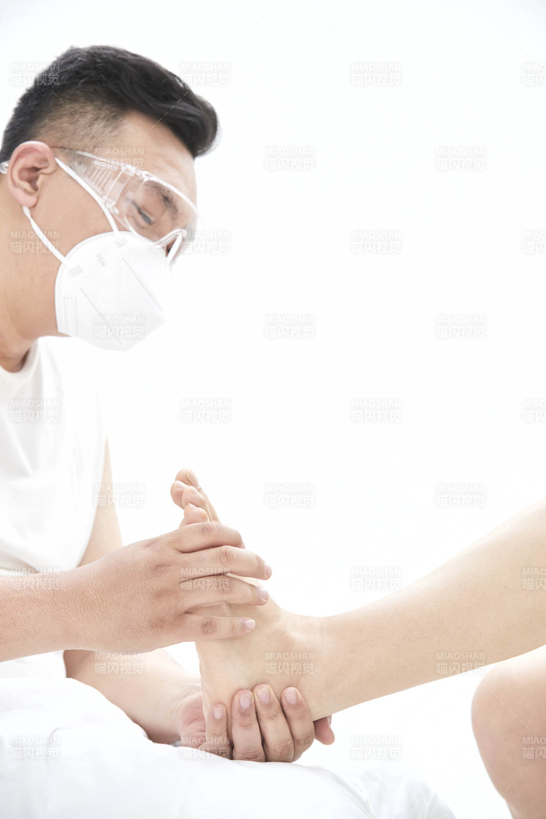 在白色背景上穿着黑色长袜的女人的苗条的腿图片