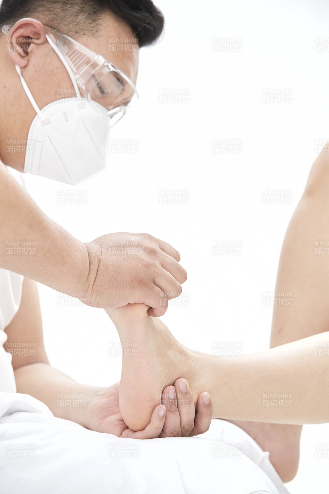 在白色背景上穿着黑色长袜的女人的苗条的腿图片