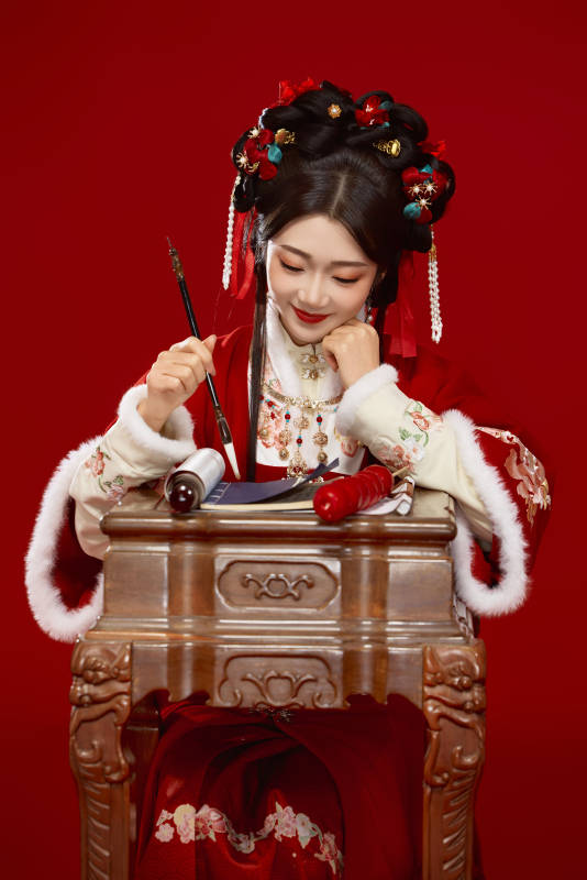 红色背景下身穿喜庆汉服认真学习的中国美女图片