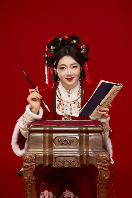 红色背景下身穿喜庆汉服认真学习的中国美女图片