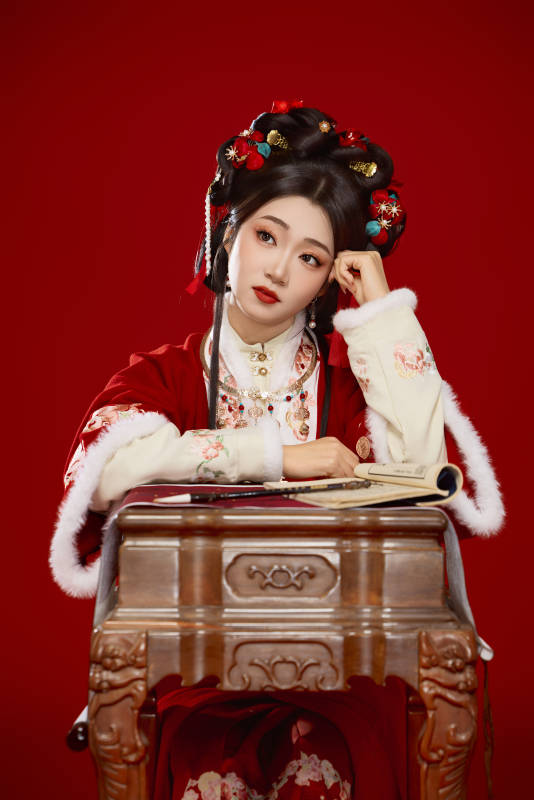 红色背景下身穿喜庆汉服认真学习的中国美女图片