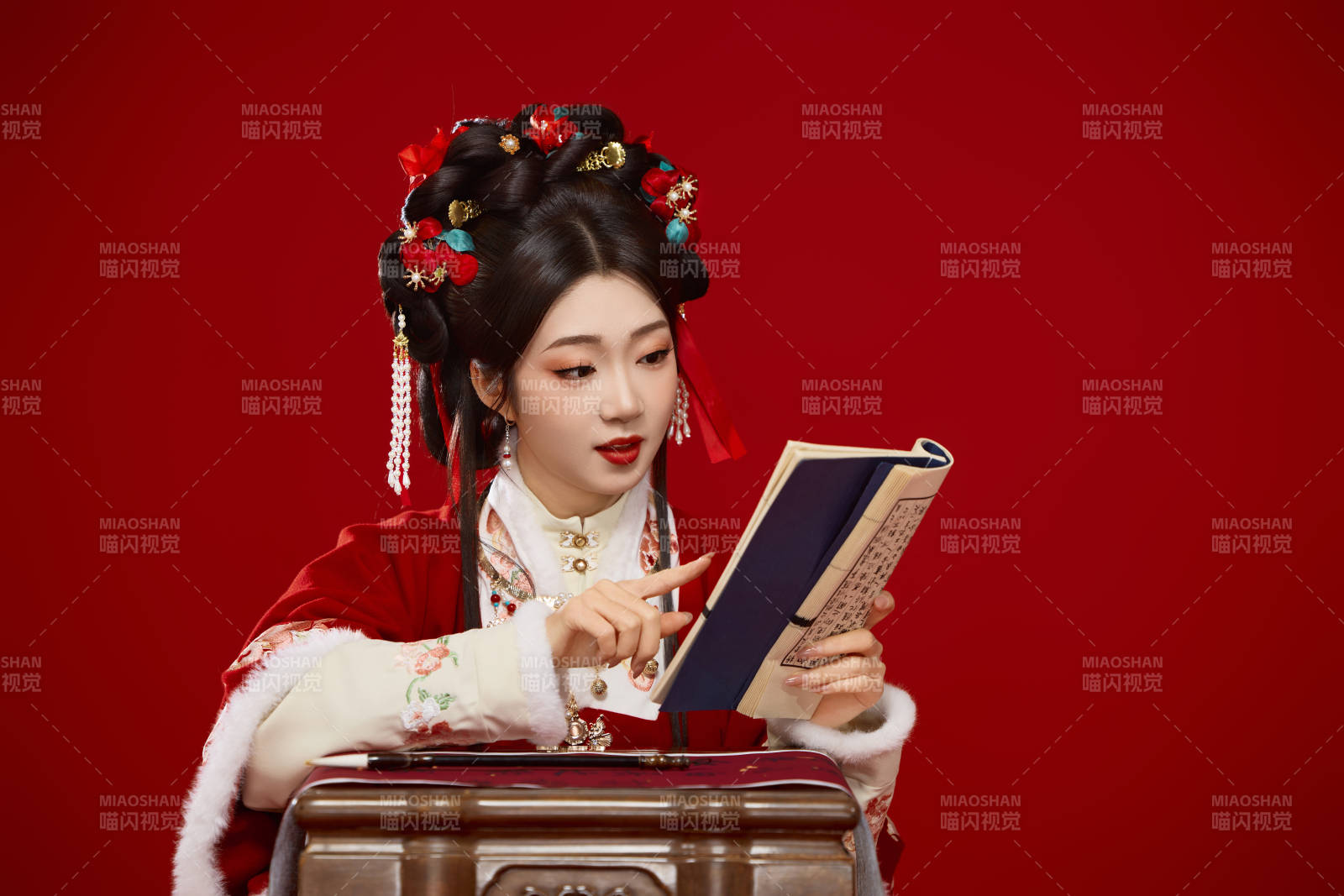 红色背景下身穿喜庆汉服认真学习的中国美女图片