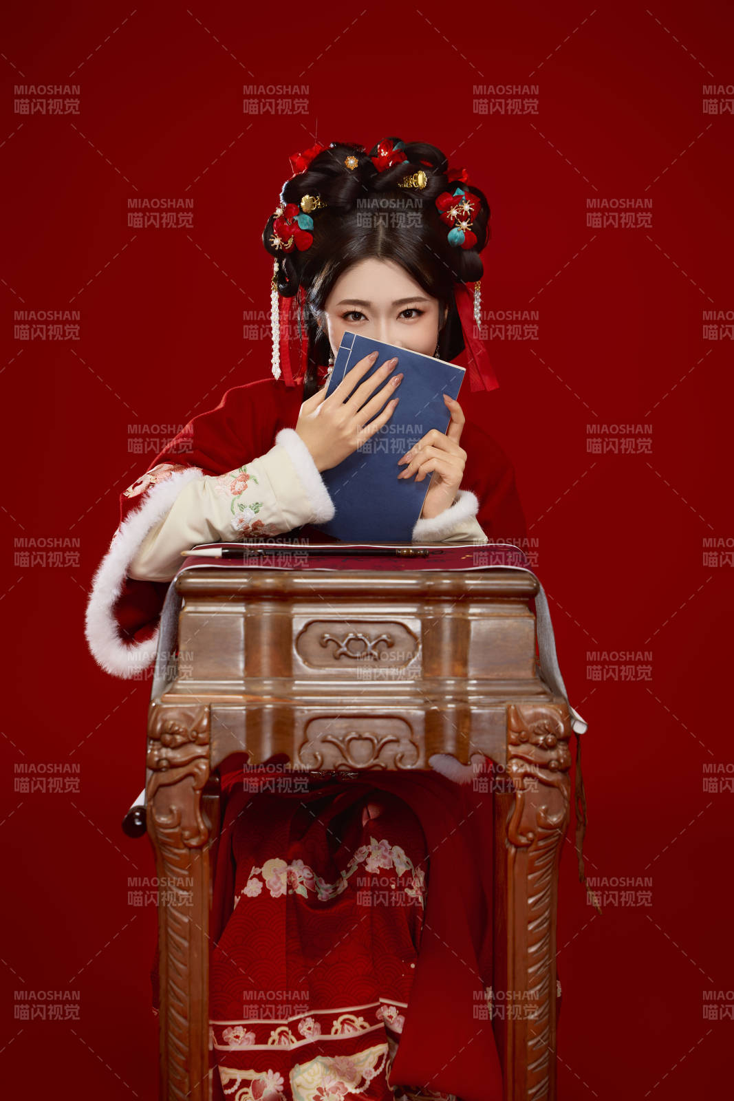 红色背景下身穿喜庆汉服认真学习的中国美女图片