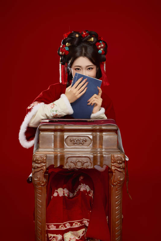 红色背景下身穿喜庆汉服认真学习的中国美女图片
