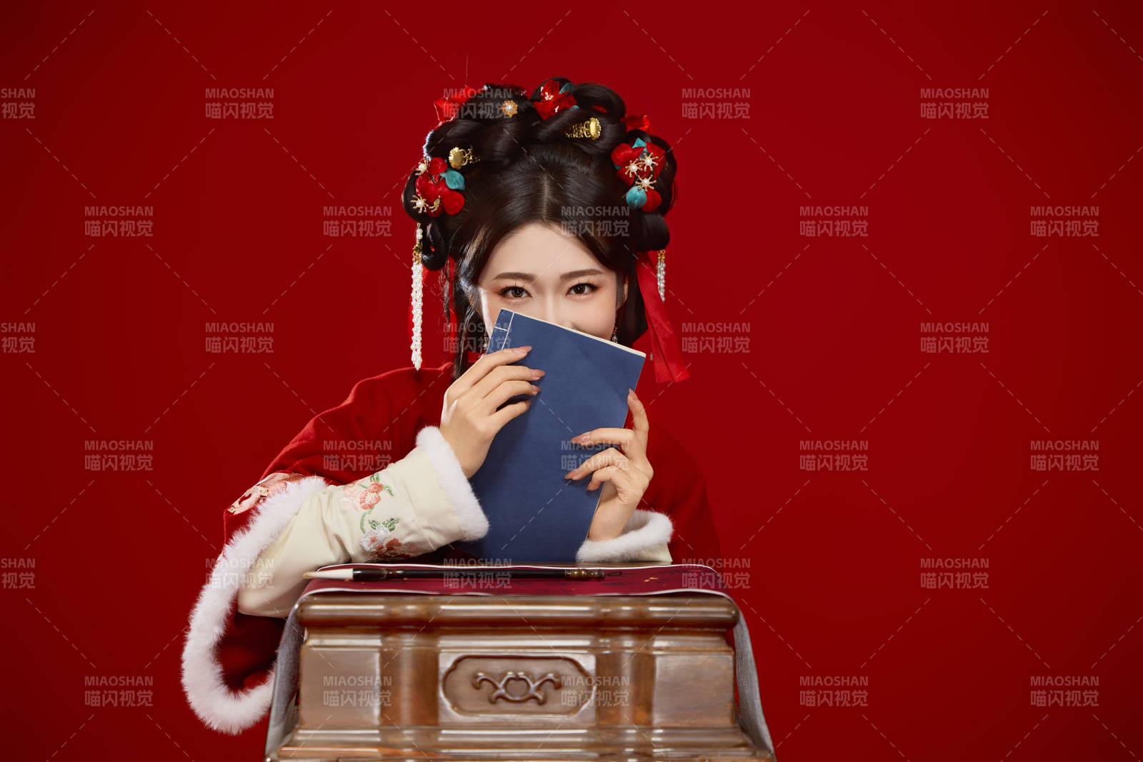 红色背景下身穿喜庆汉服认真学习的中国美女图片