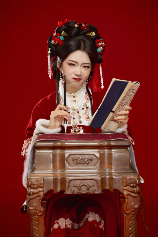 红色背景下身穿喜庆汉服认真学习的中国美女图片