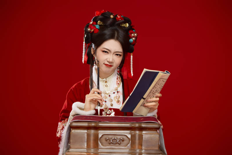 红色背景下身穿喜庆汉服认真学习的中国美女图片
