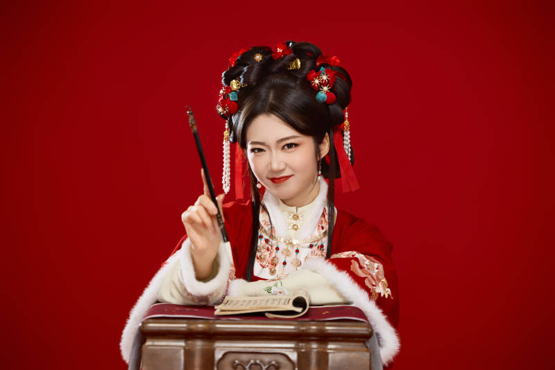 红色背景下身穿喜庆汉服认真学习的中国美女图片
