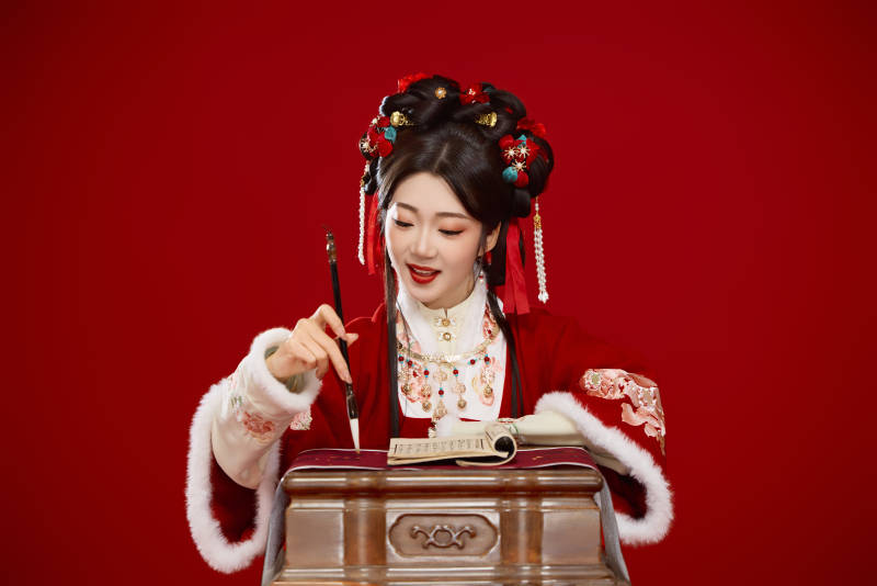 红色背景下身穿喜庆汉服认真学习的中国美女图片