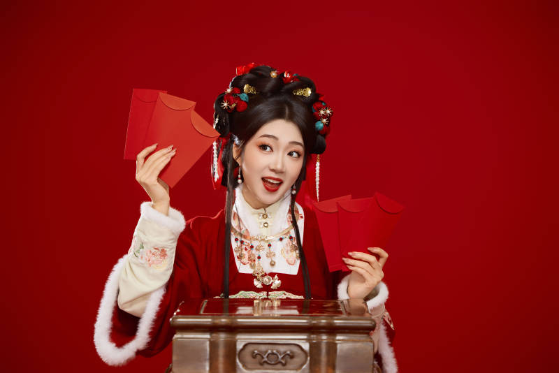 红色背景下身穿汉服手拿红包拜年的中国美女图片