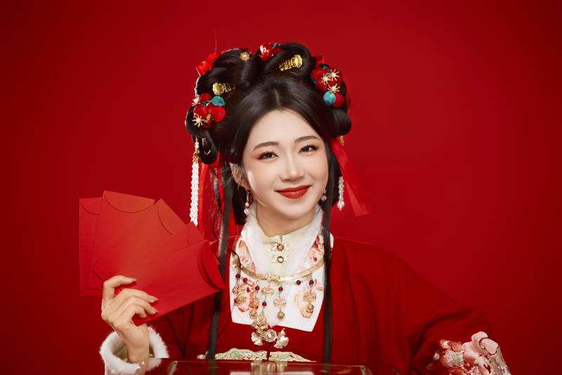 红色背景下身穿汉服手拿红包拜年的中国美女图片