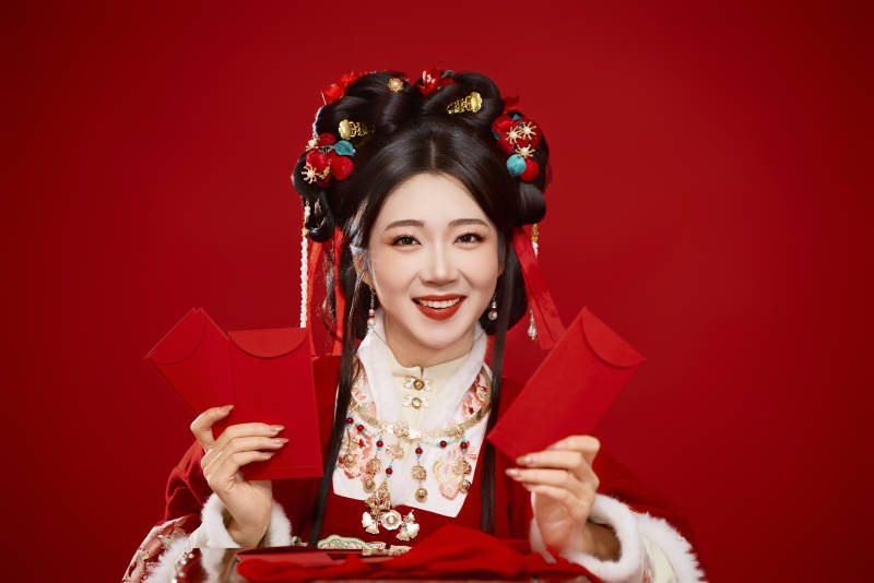 红色背景下身穿汉服手拿红包拜年的中国美女图片