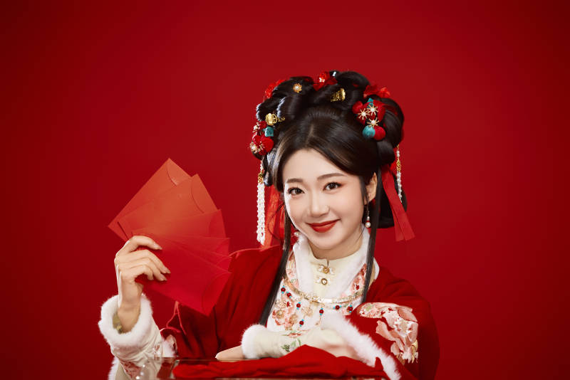 红色背景下身穿汉服手拿红包拜年的中国美女图片