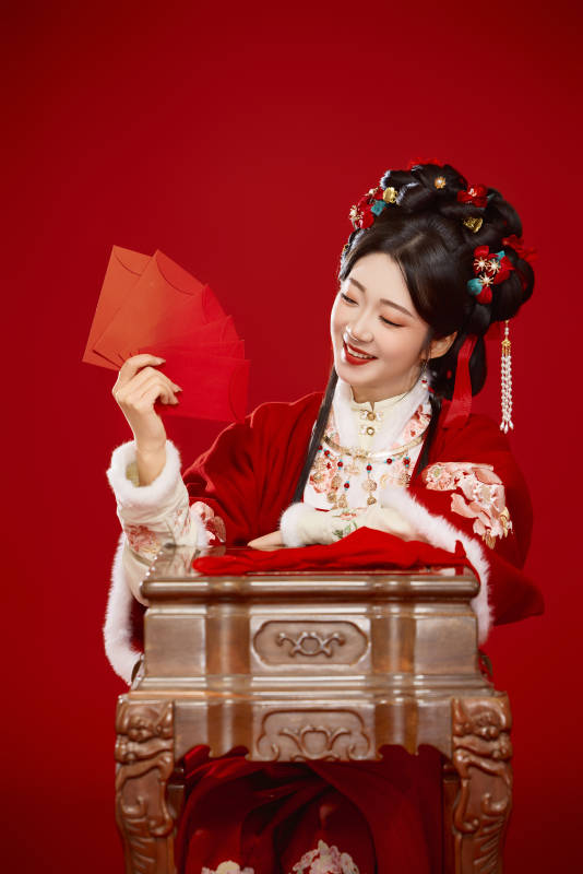 红色背景下身穿汉服手拿红包拜年的中国美女图片