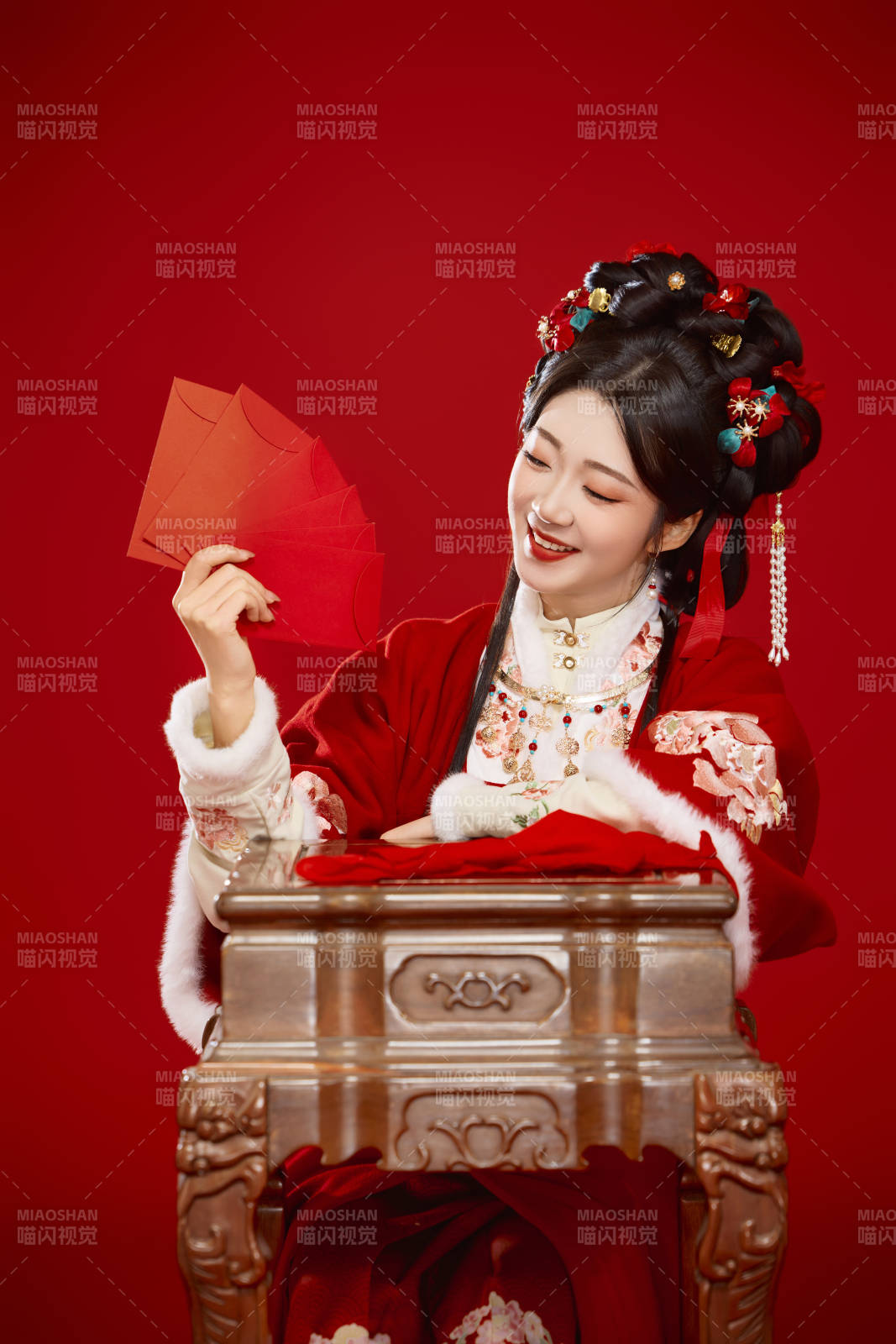 红色背景下身穿汉服手拿红包拜年的中国美女图片