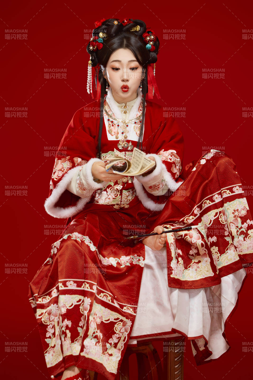 红色背景下身穿喜庆汉服认真学习的中国美女图片