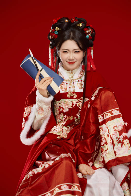 红色背景下身穿喜庆汉服认真学习的中国美女图片