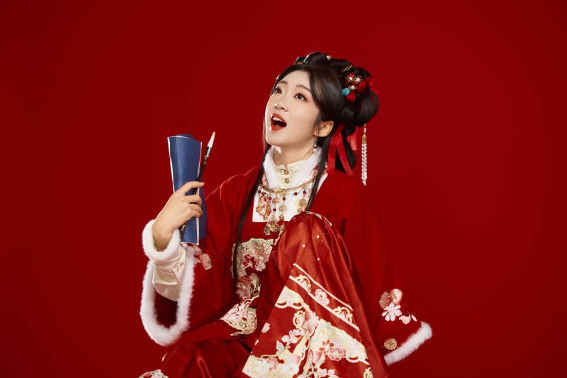 红色背景下身穿喜庆汉服认真学习的中国美女图片