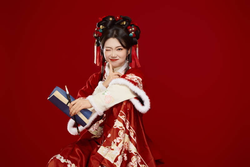 红色背景下身穿喜庆汉服认真学习的中国美女图片
