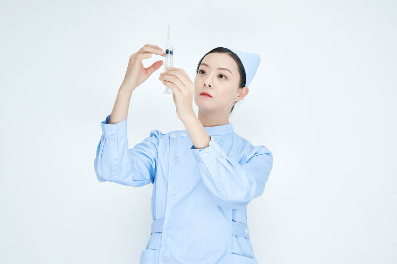 穿护士服戴口罩手执针筒的年轻女护士图片