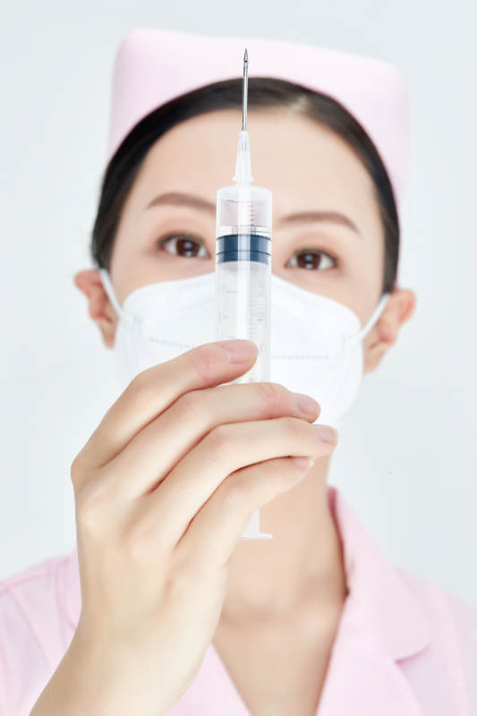 穿护士服戴口罩手执针筒的年轻女护士图片