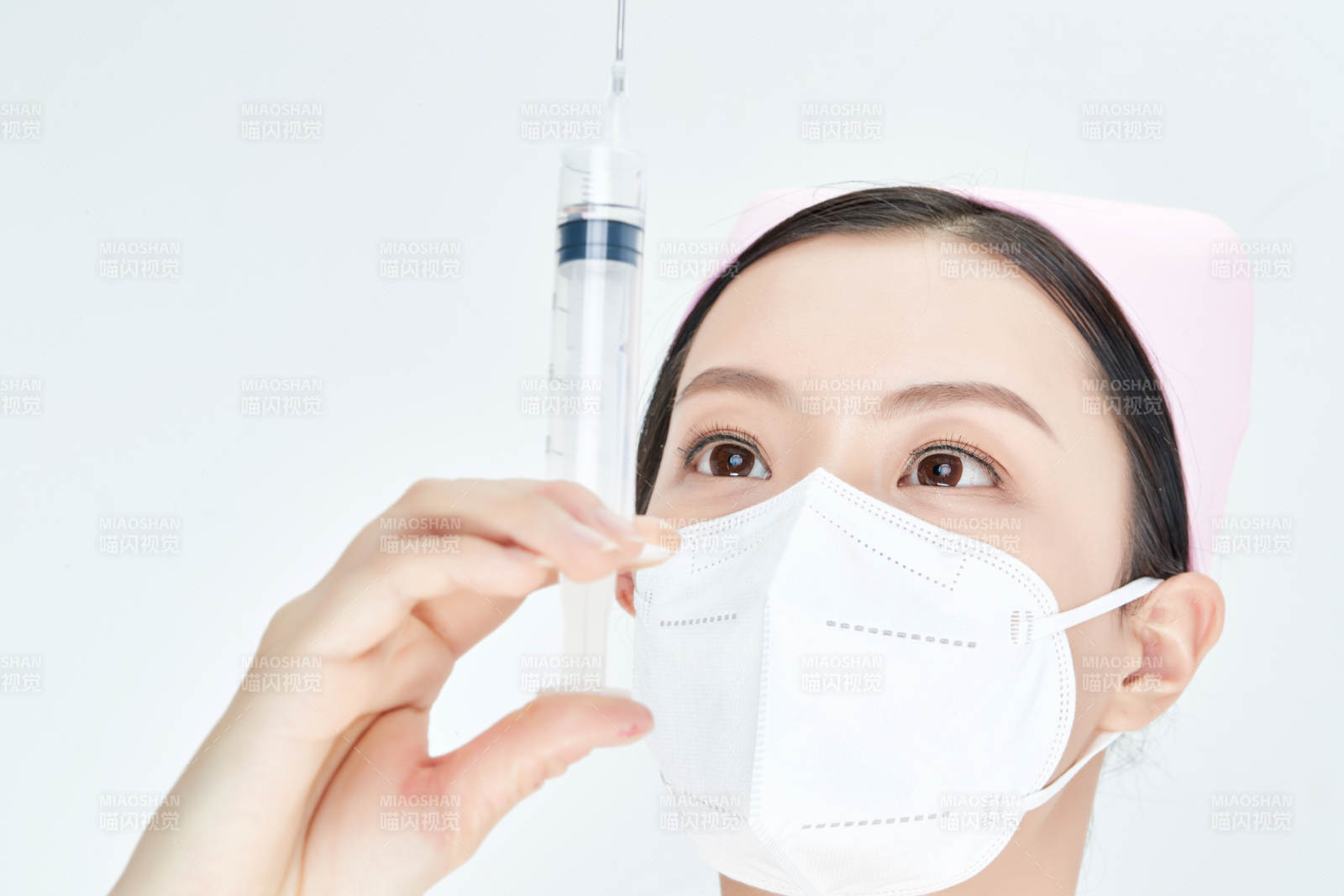 穿护士服戴口罩手执针筒的年轻女护士图片