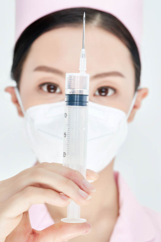 穿护士服戴口罩手执针筒的年轻女护士图片