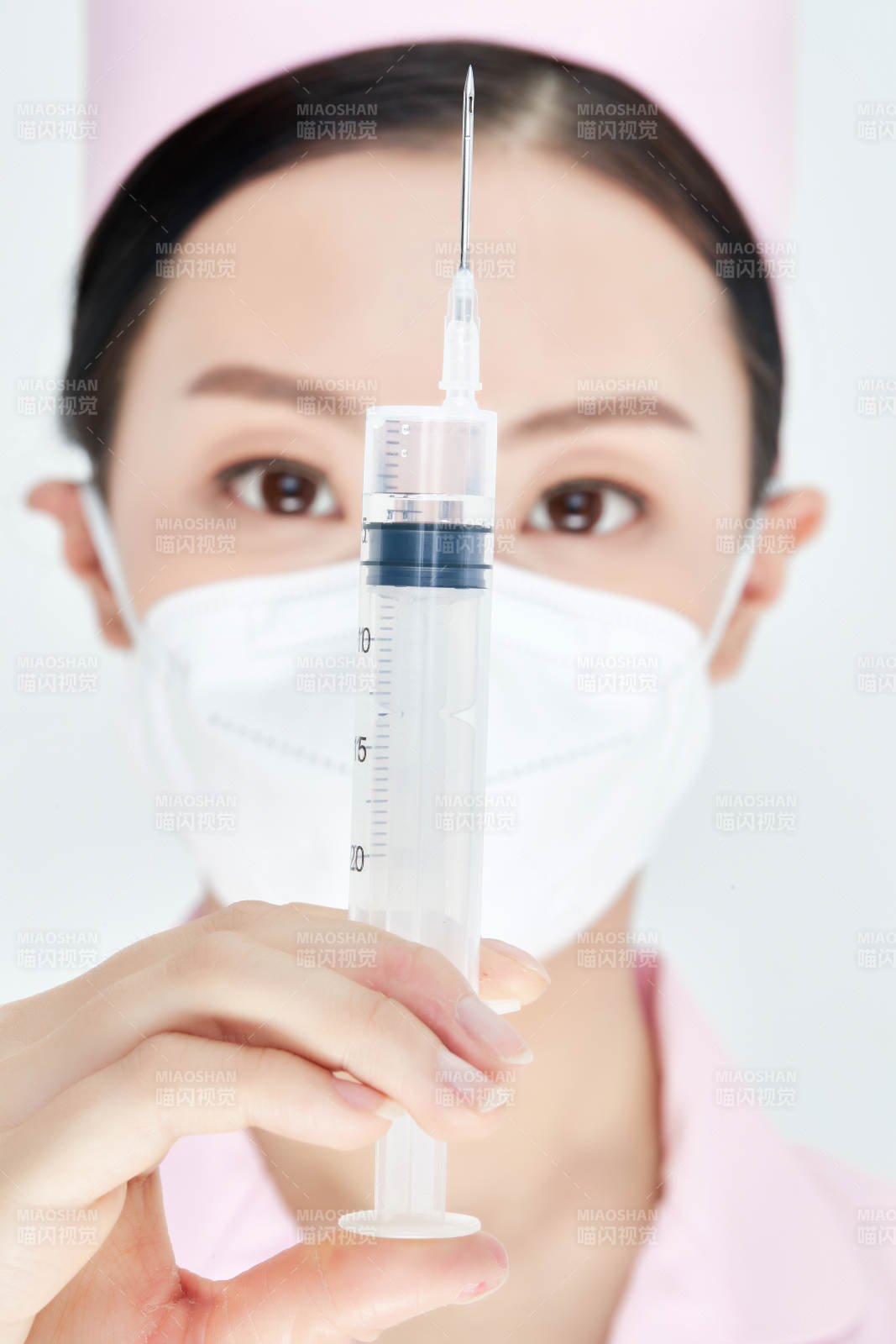 穿护士服戴口罩手执针筒的年轻女护士图片