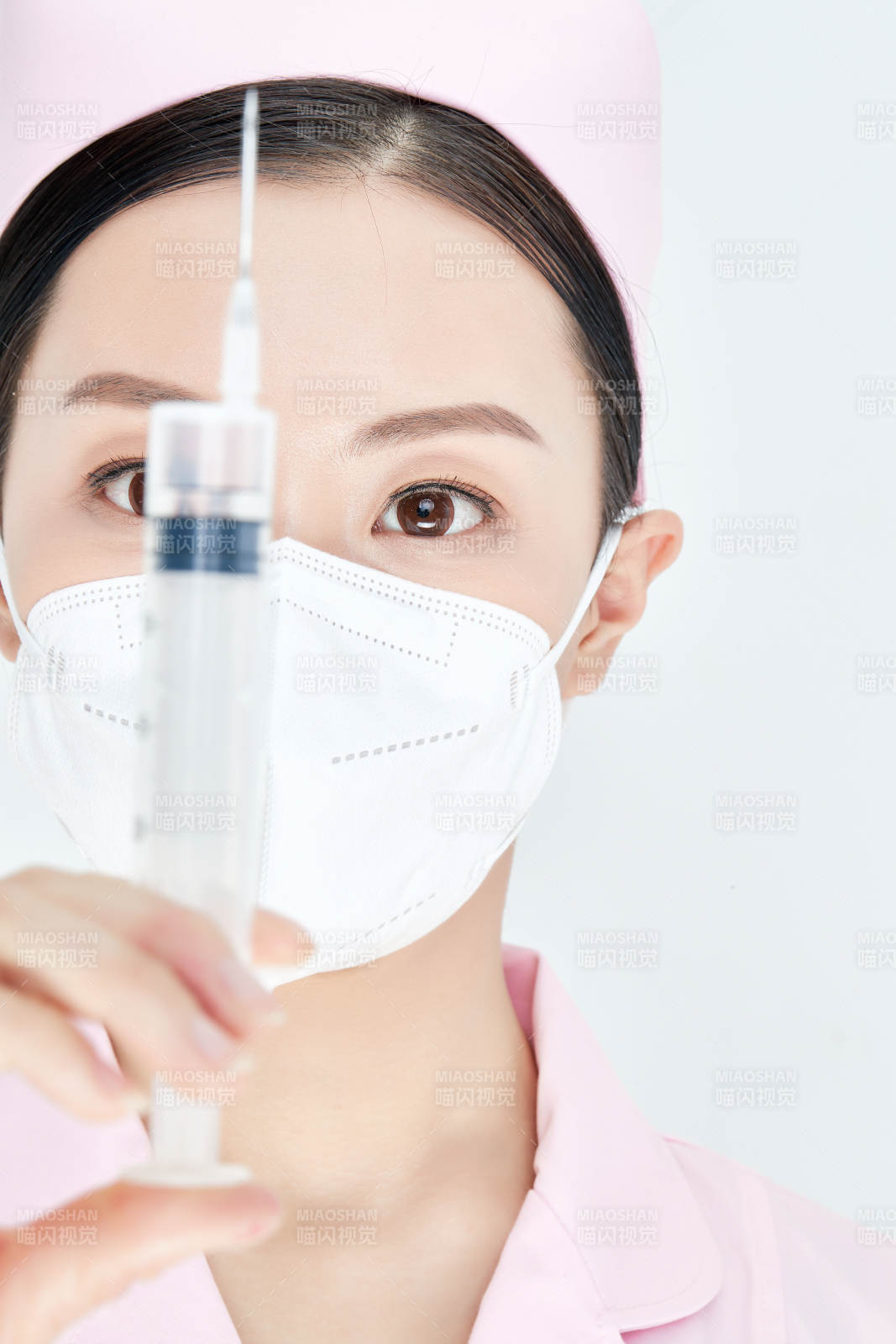 穿护士服戴口罩手执针筒的年轻女护士图片