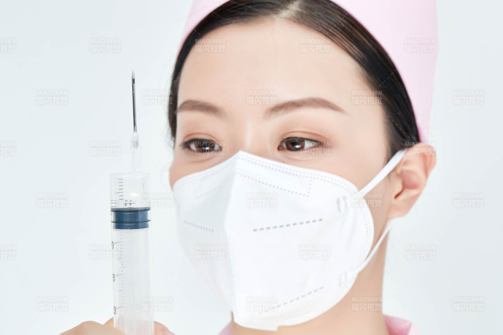 穿护士服戴口罩手执针筒的年轻女护士图片