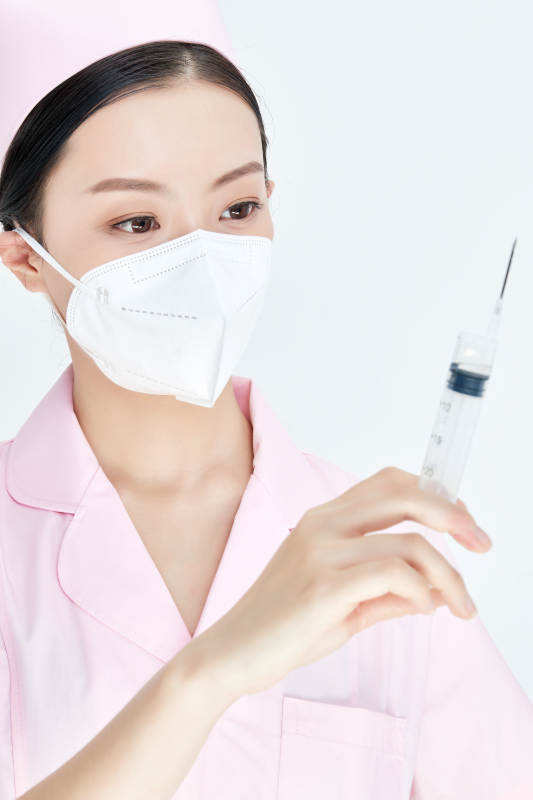 穿护士服戴口罩手执针筒的年轻女护士图片