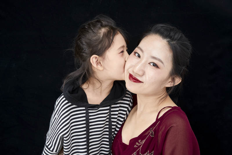 黑色背景的美丽妈妈与可爱女儿亲子人像图片