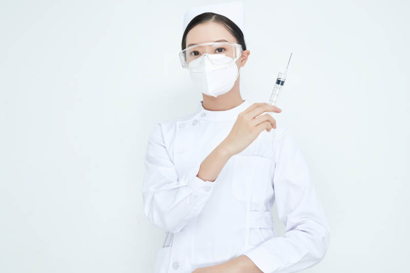穿护士服戴口罩手执针筒的年轻女护士图片