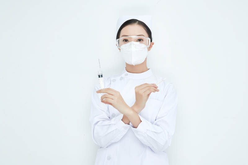 穿护士服戴口罩手执针筒的年轻女护士图片