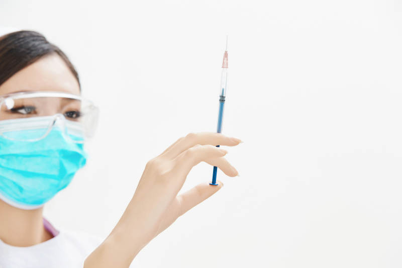 穿护士服戴口罩手执针筒的年轻女护士图片