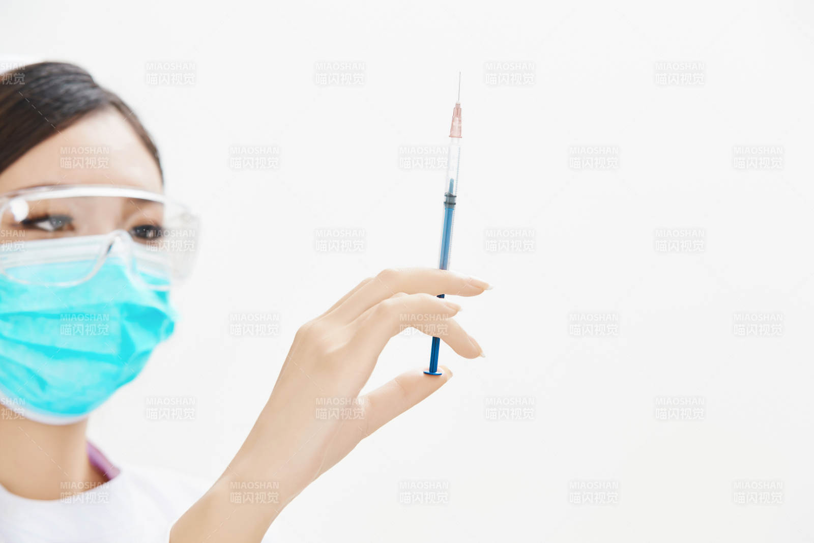 穿护士服戴口罩手执针筒的年轻女护士图片