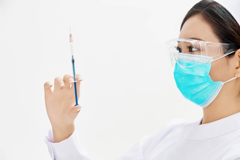 穿护士服戴口罩手执针筒的年轻女护士图片