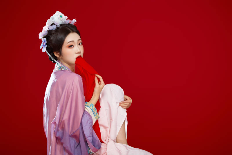 红色背景下身穿中国明朝簪花发饰汉服的美女图片