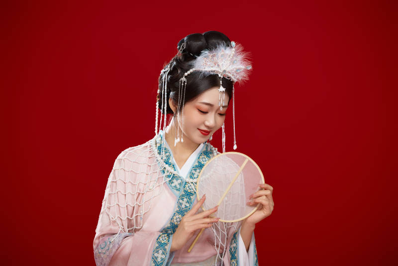 红色背景下身穿中国明朝簪花发饰汉服的美女图片