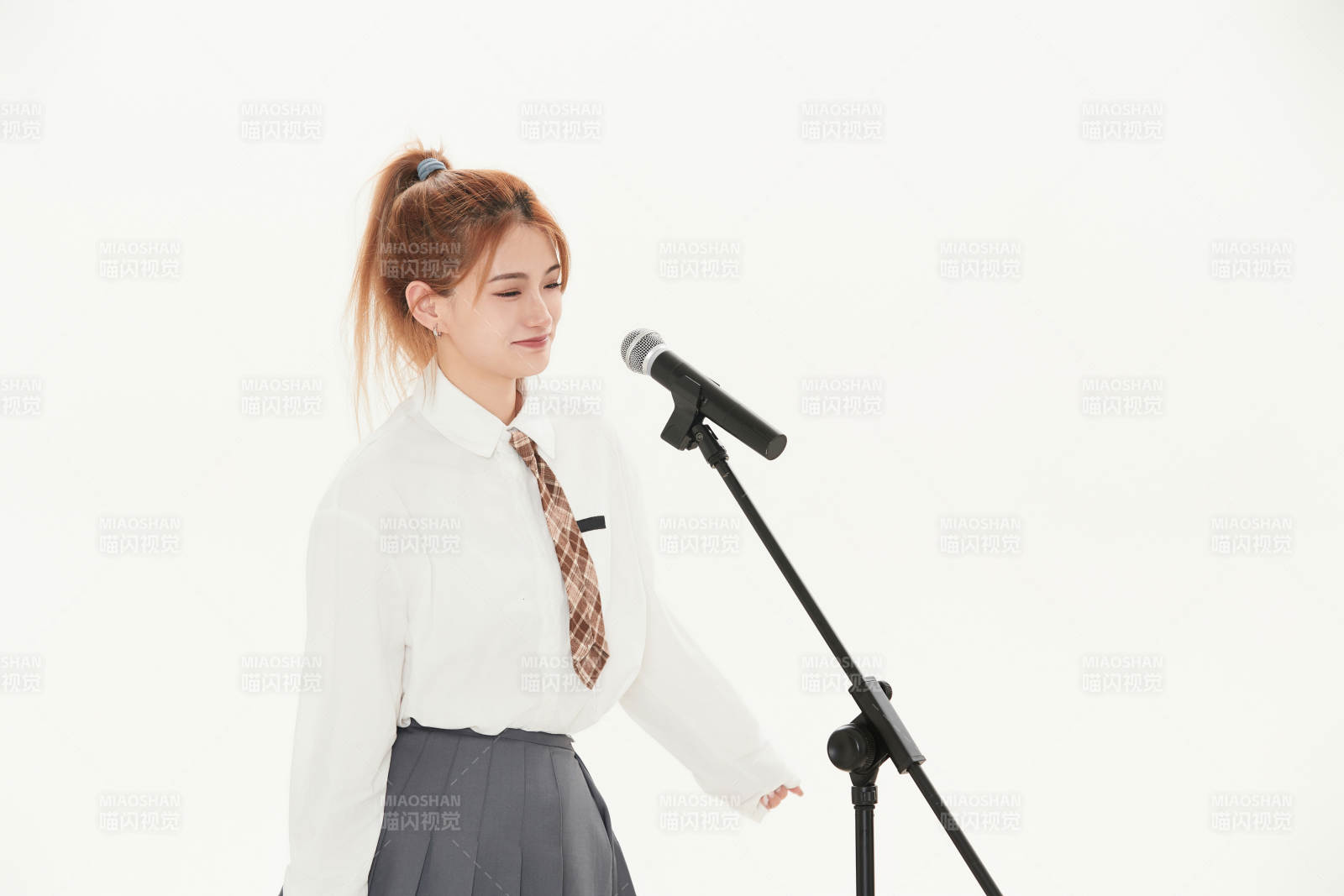 白色背景下站在麦克风前唱歌的亚洲女性图片