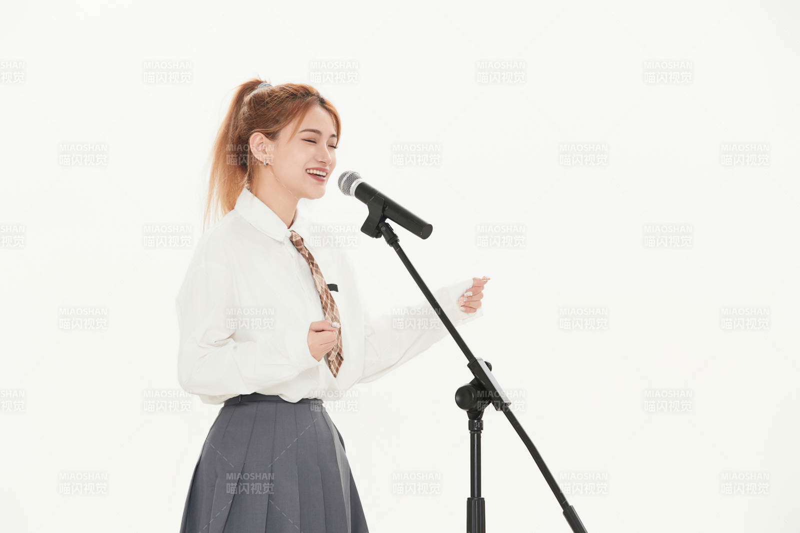 白色背景下站在麦克风前唱歌的亚洲女性图片