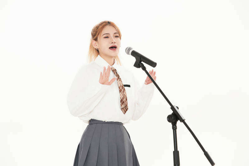 白色背景下站在麦克风前唱歌的亚洲女性图片